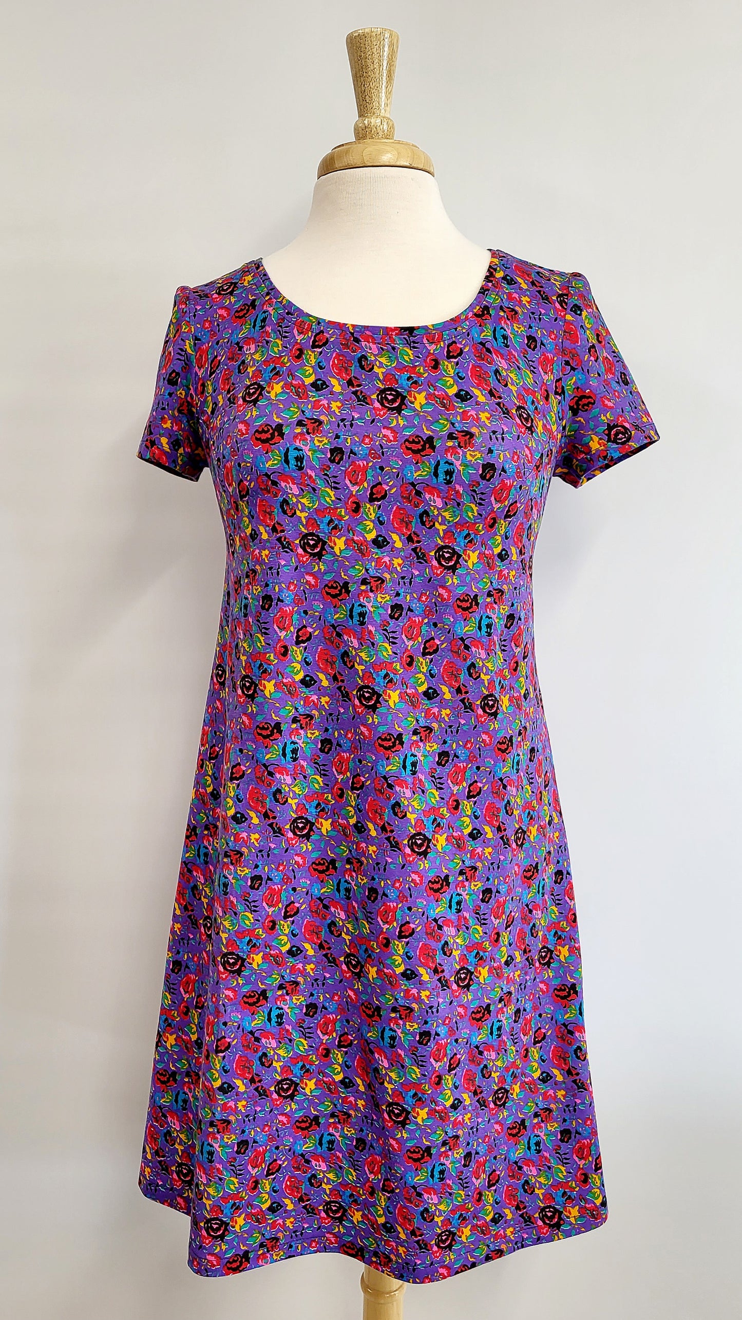 “Christine” dress in cotton jersey, small colorful flowers on a mauve background.