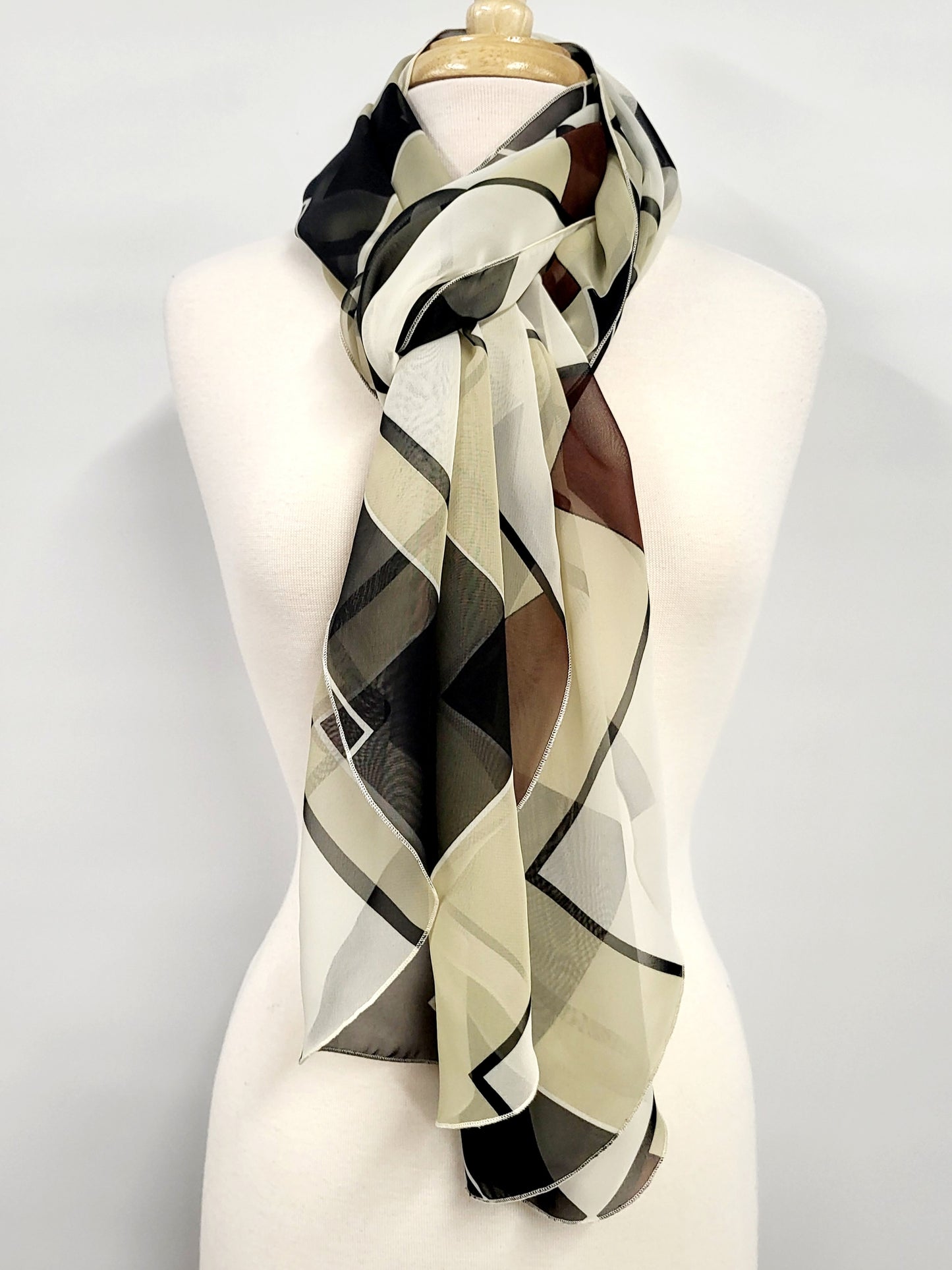 Long, lightweight scarf with geometric patterns in earth tones and black