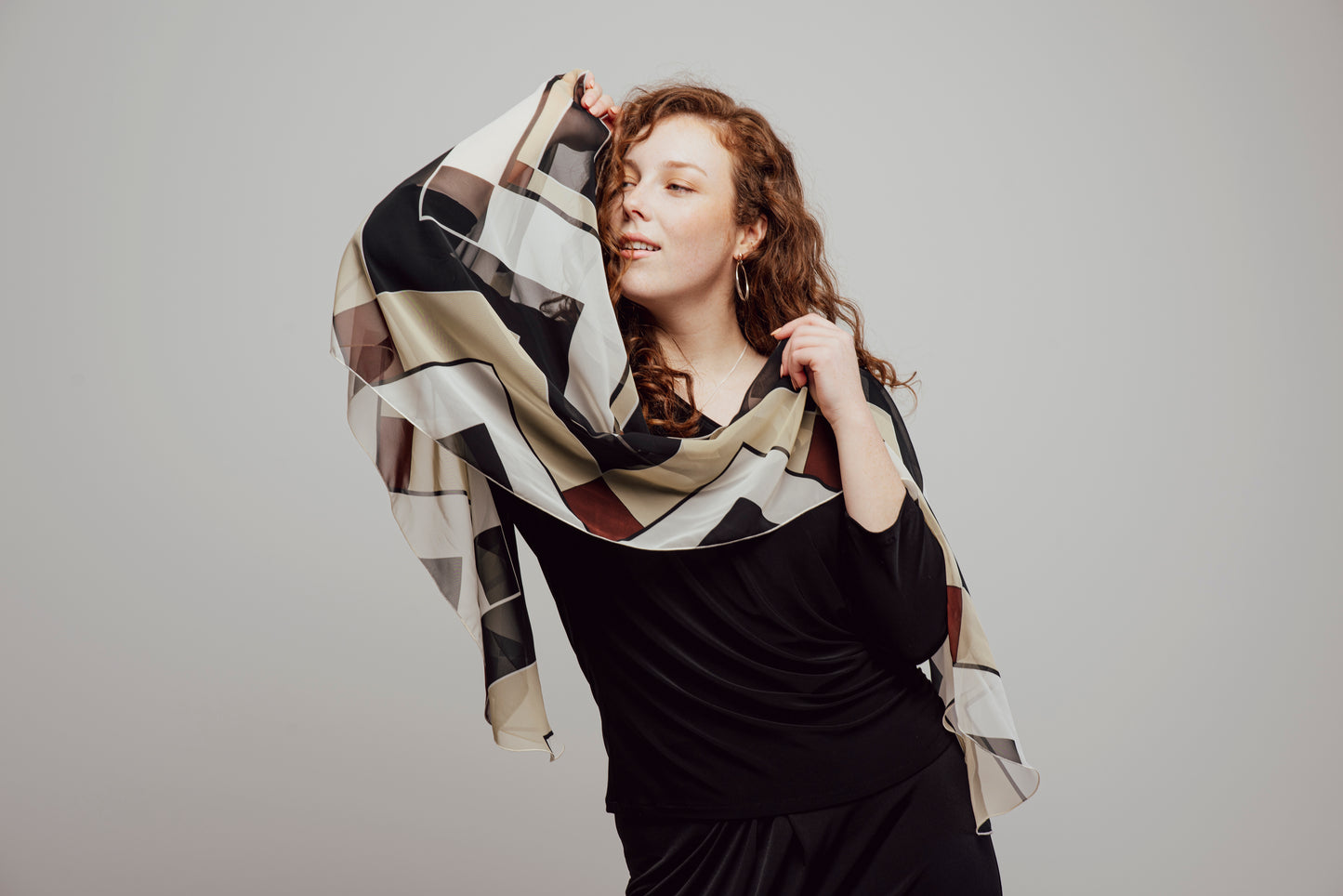 Long, lightweight scarf with geometric patterns in earth tones and black