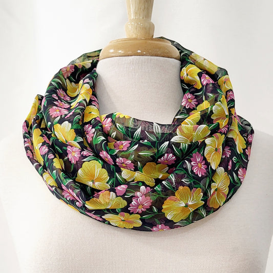 Foulard circulaire imprimé de fleurs jaunes, roses et feuillage vert.