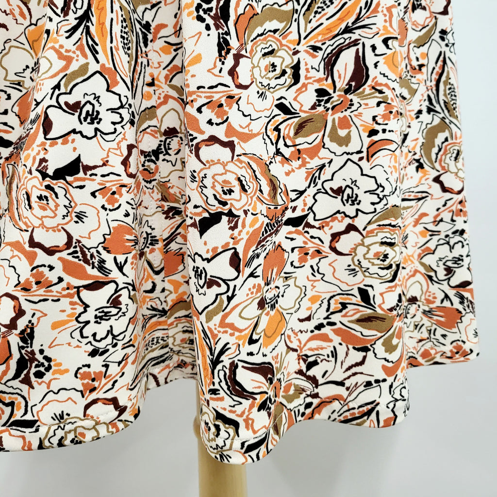 Alice dress with warm-toned print on a white background