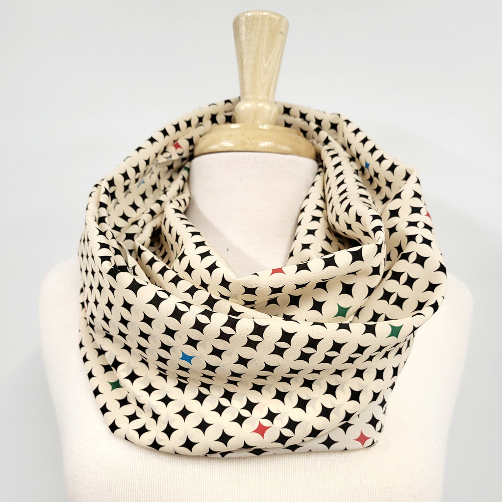 Foulard circulaire en soie, crème et noir avec petites touches de couleurs.