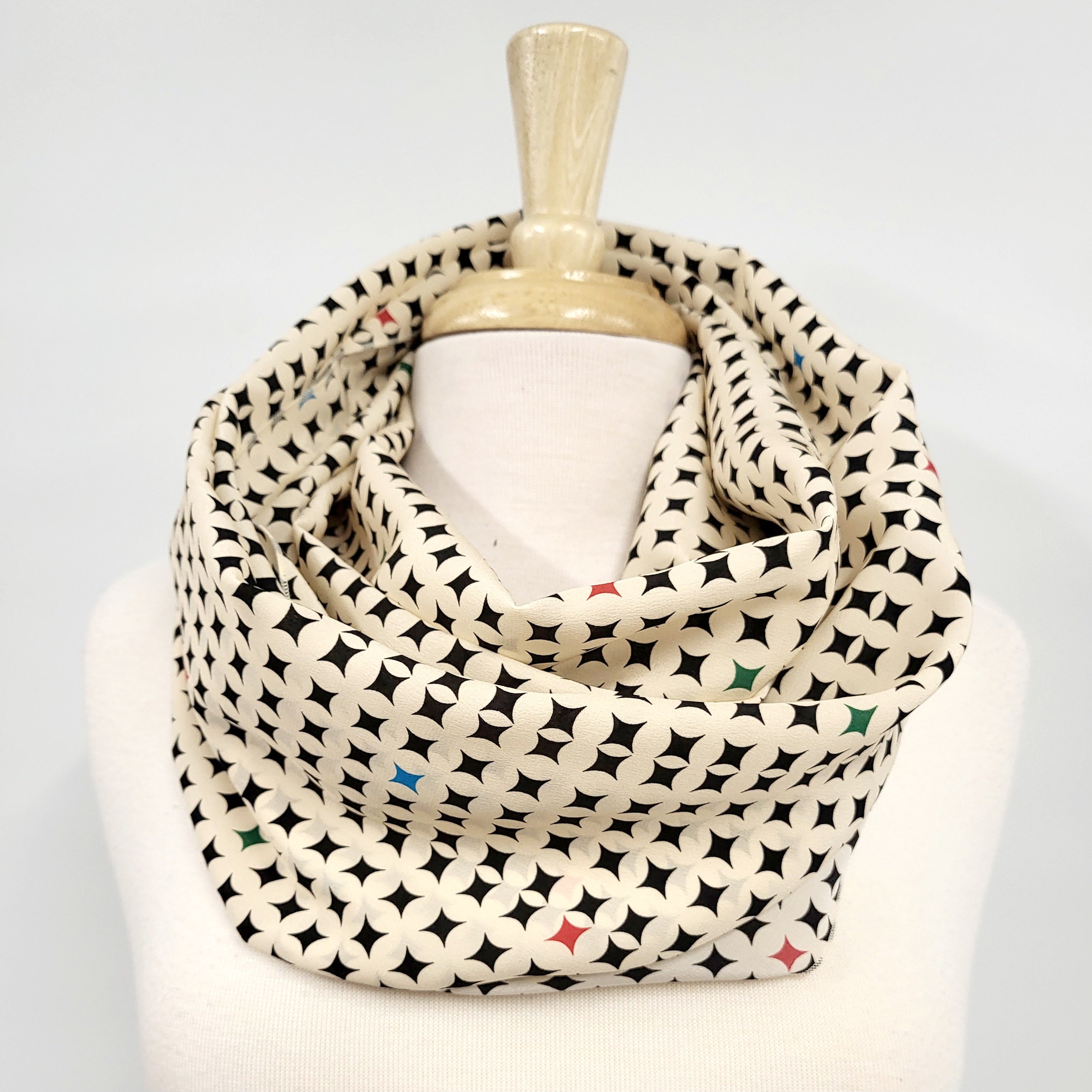 Foulard circulaire en soie, crème et noir avec petites touches de couleurs.