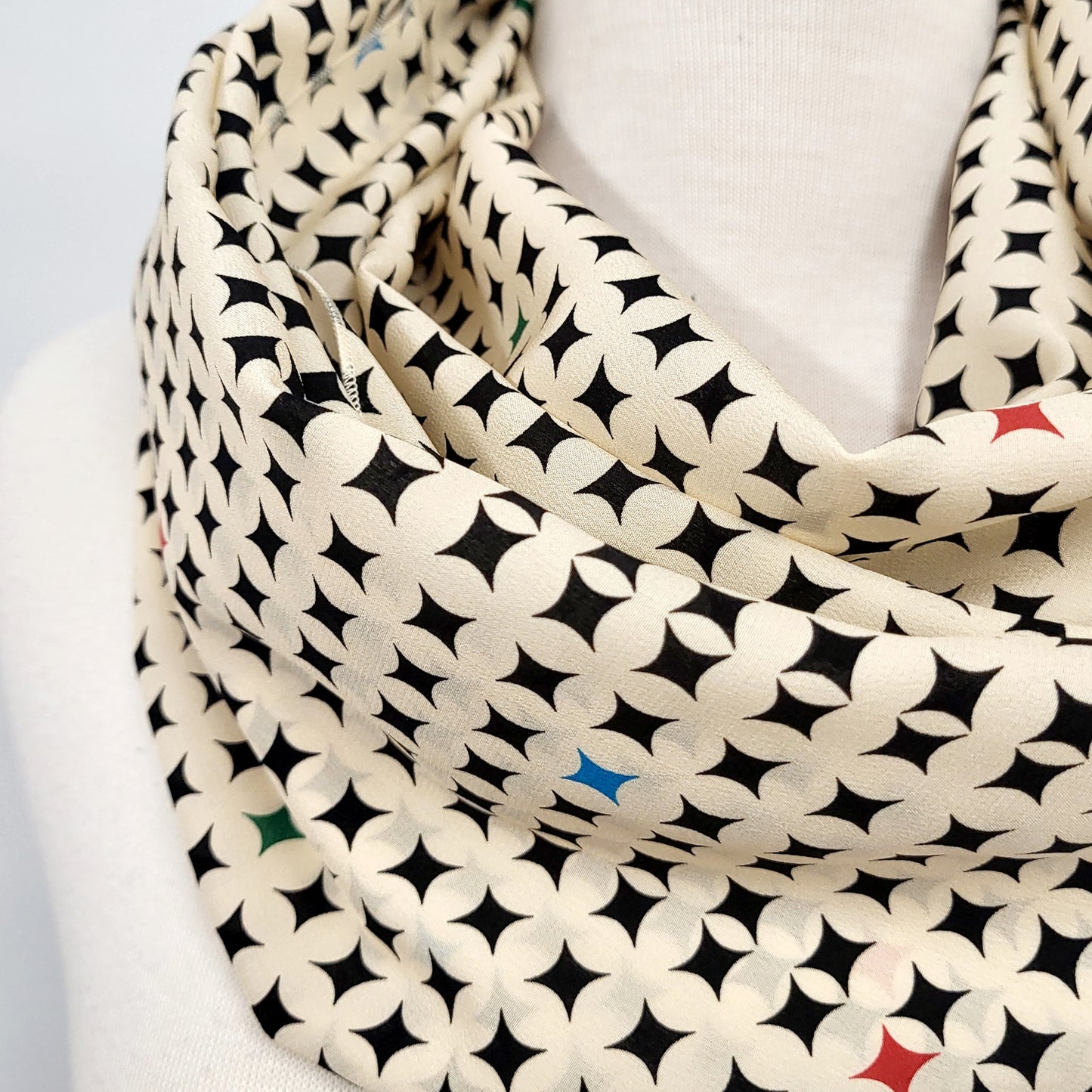 Foulard circulaire en soie, crème et noir avec petites touches de couleurs.
