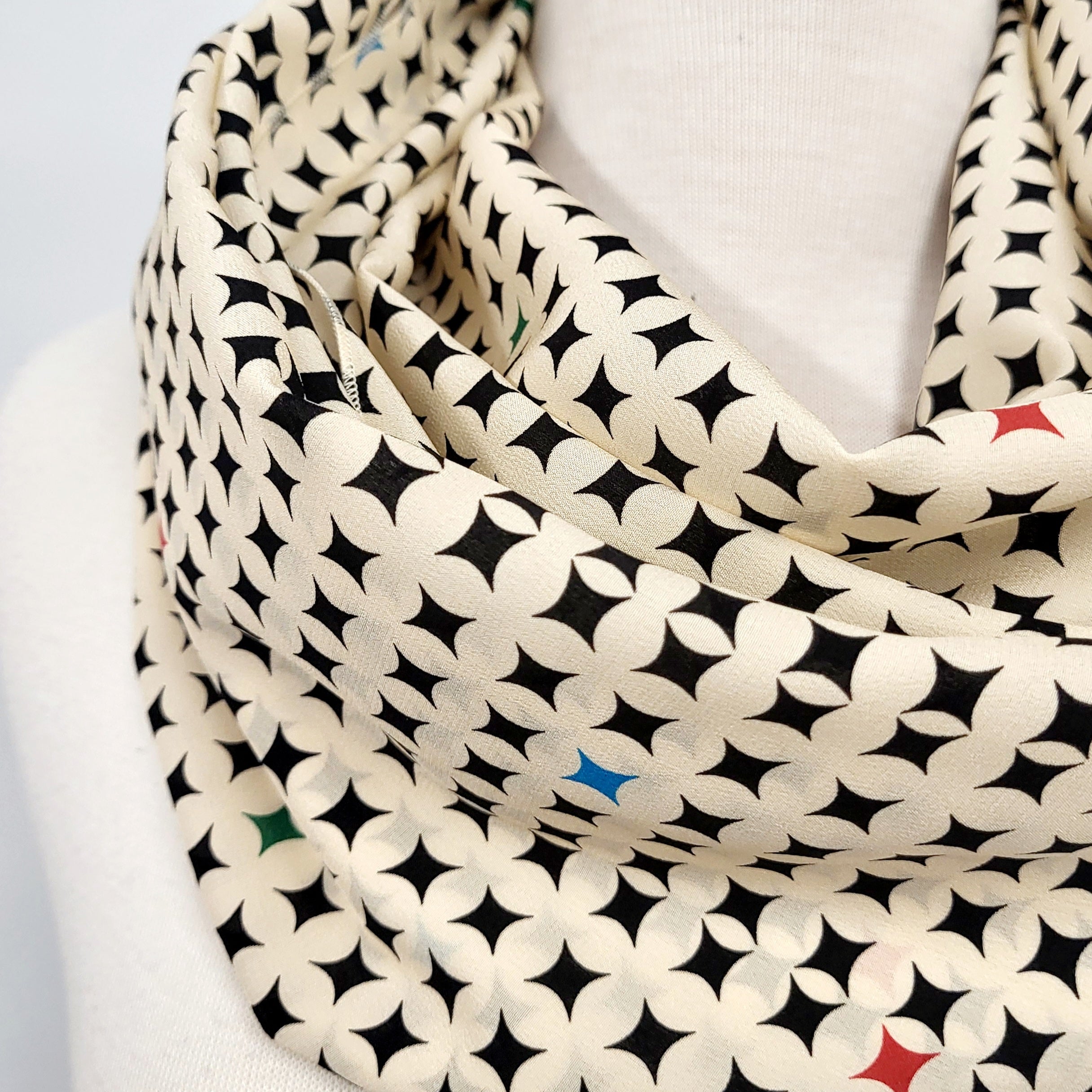 Foulard circulaire en soie, crème et noir avec petites touches de couleurs.