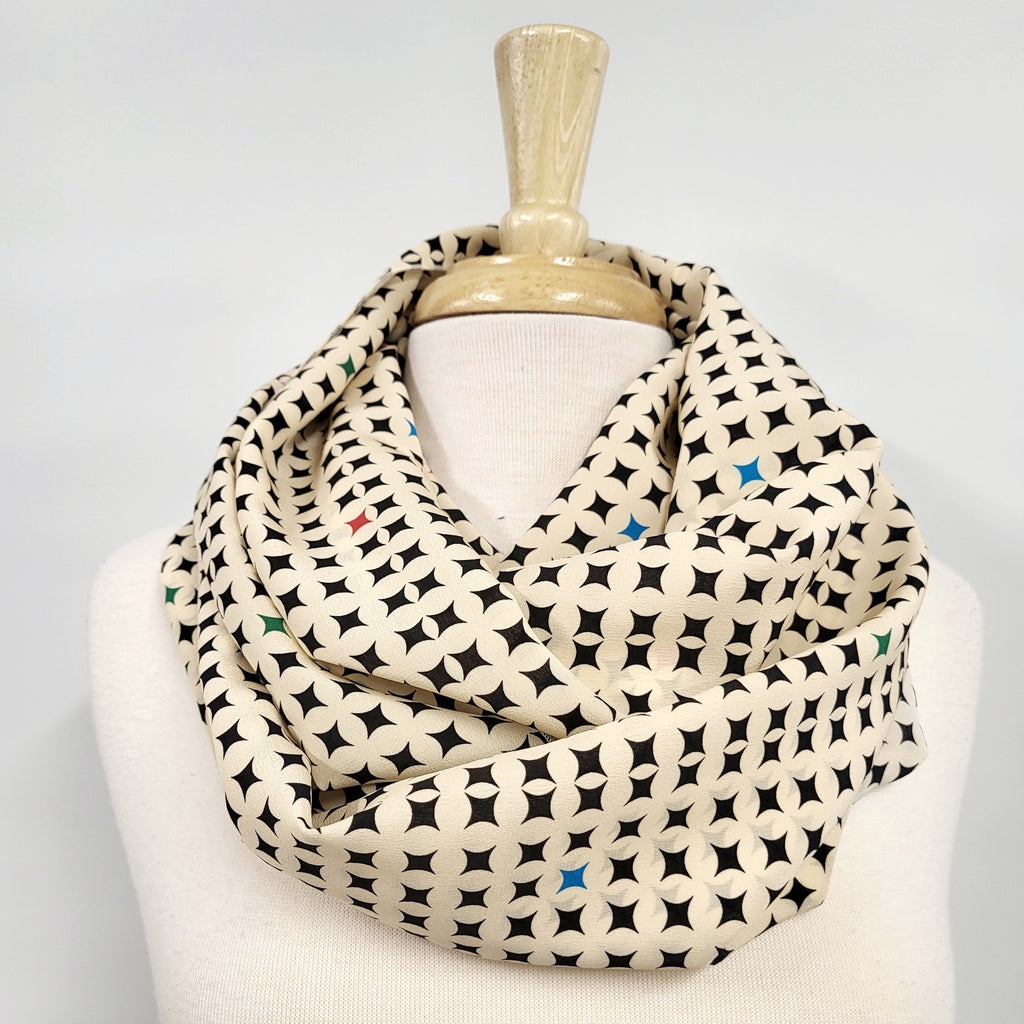 Foulard circulaire en soie, crème et noir avec petites touches de couleurs.