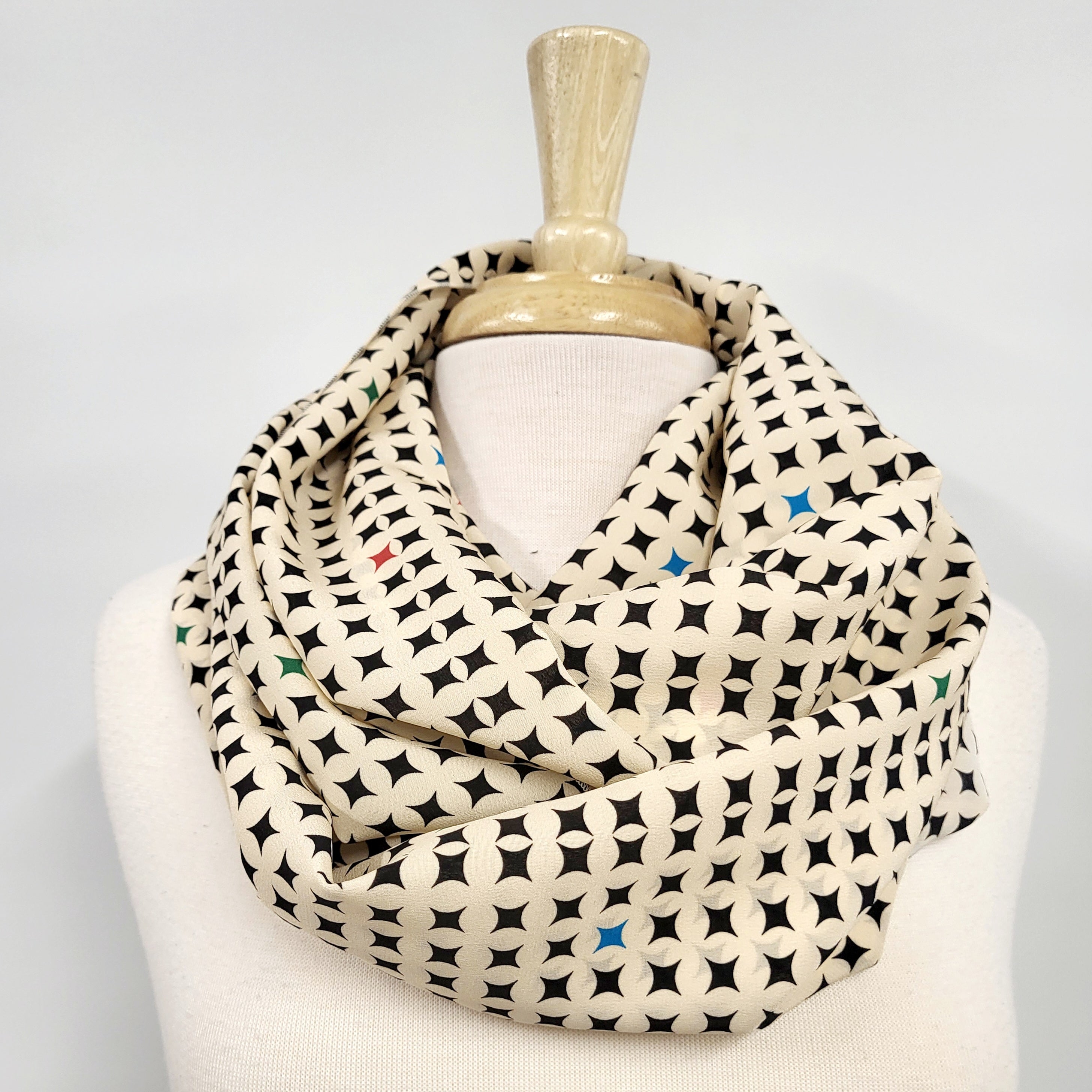 Foulard circulaire en soie, crème et noir avec petites touches de couleurs.