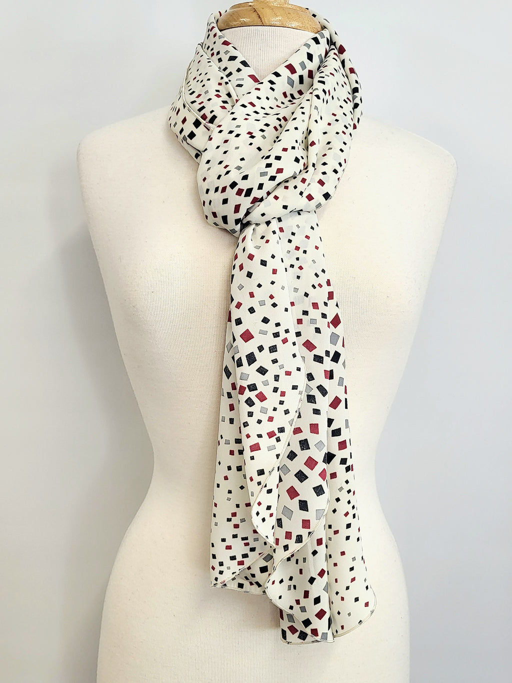 Foulard long imprimé de petits carrés noir, gris et bourgogne sur fond écru.