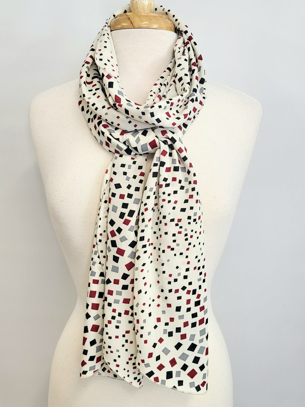 Foulard long imprimé de petits carrés noir, gris et bourgogne sur fond écru.