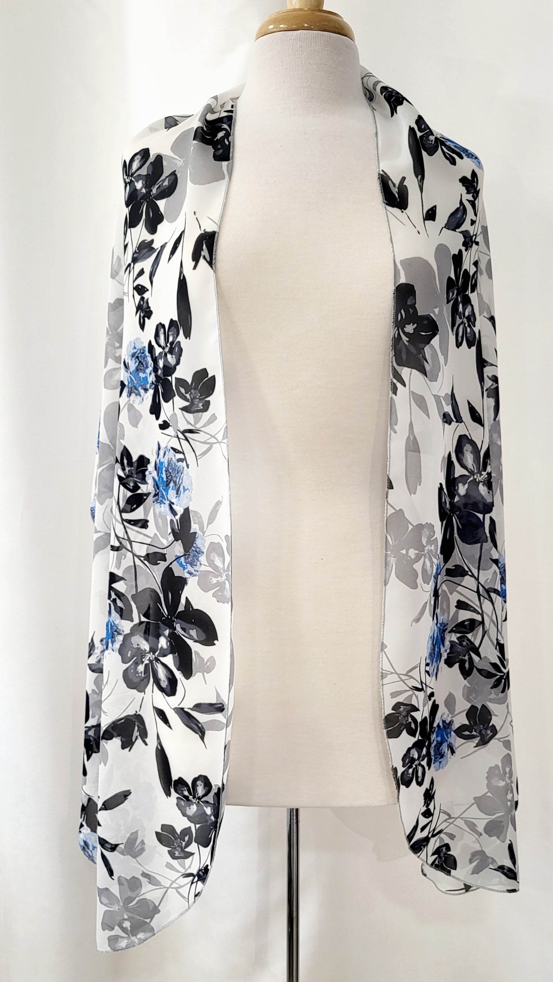 Grand foulard en voilage imprimée de fleurs grises, noires et bleues.