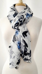 Grand foulard en voilage imprimée de fleurs grises, noires et bleues.