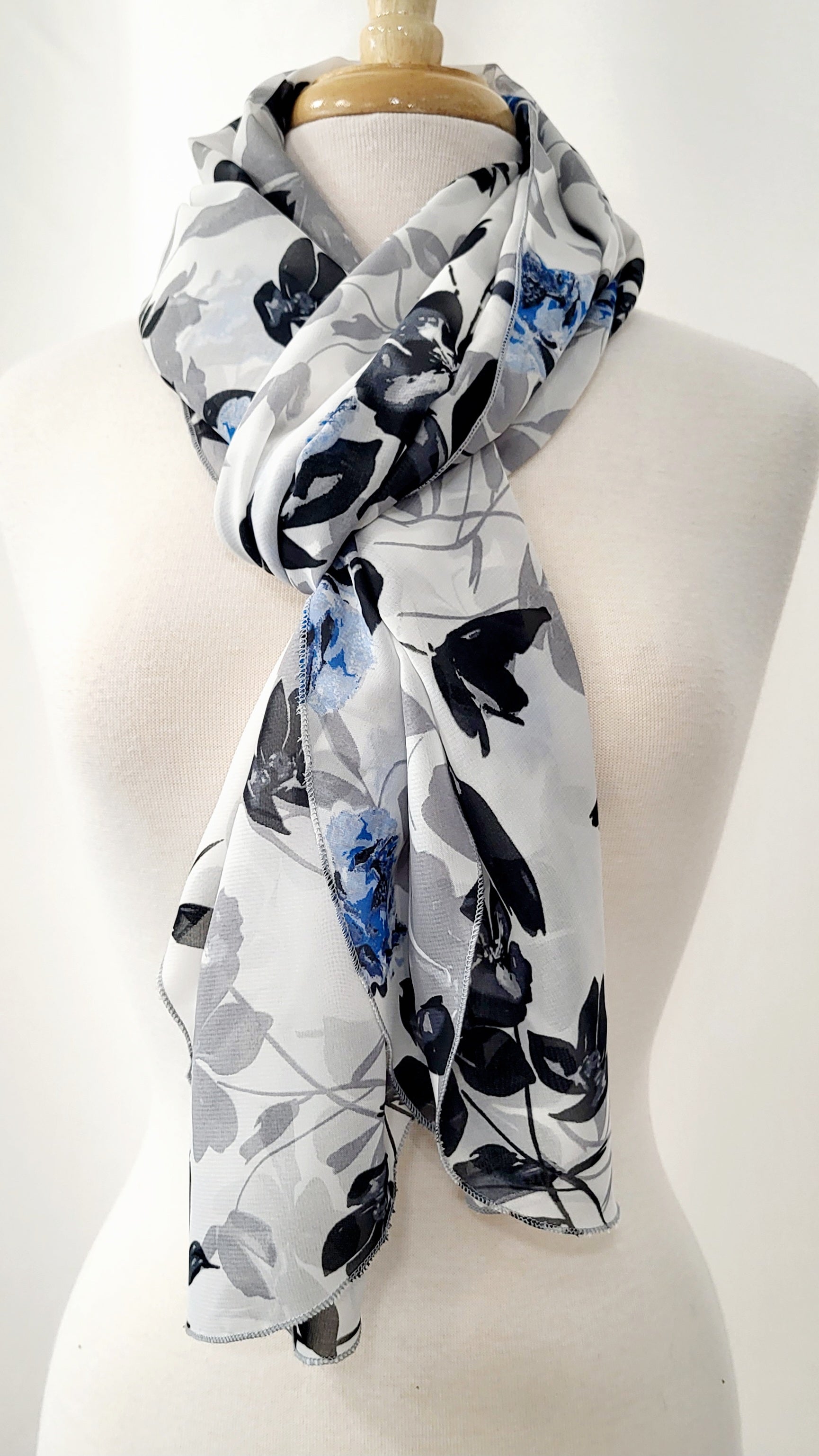 Grand foulard en voilage imprimée de fleurs grises, noires et bleues.