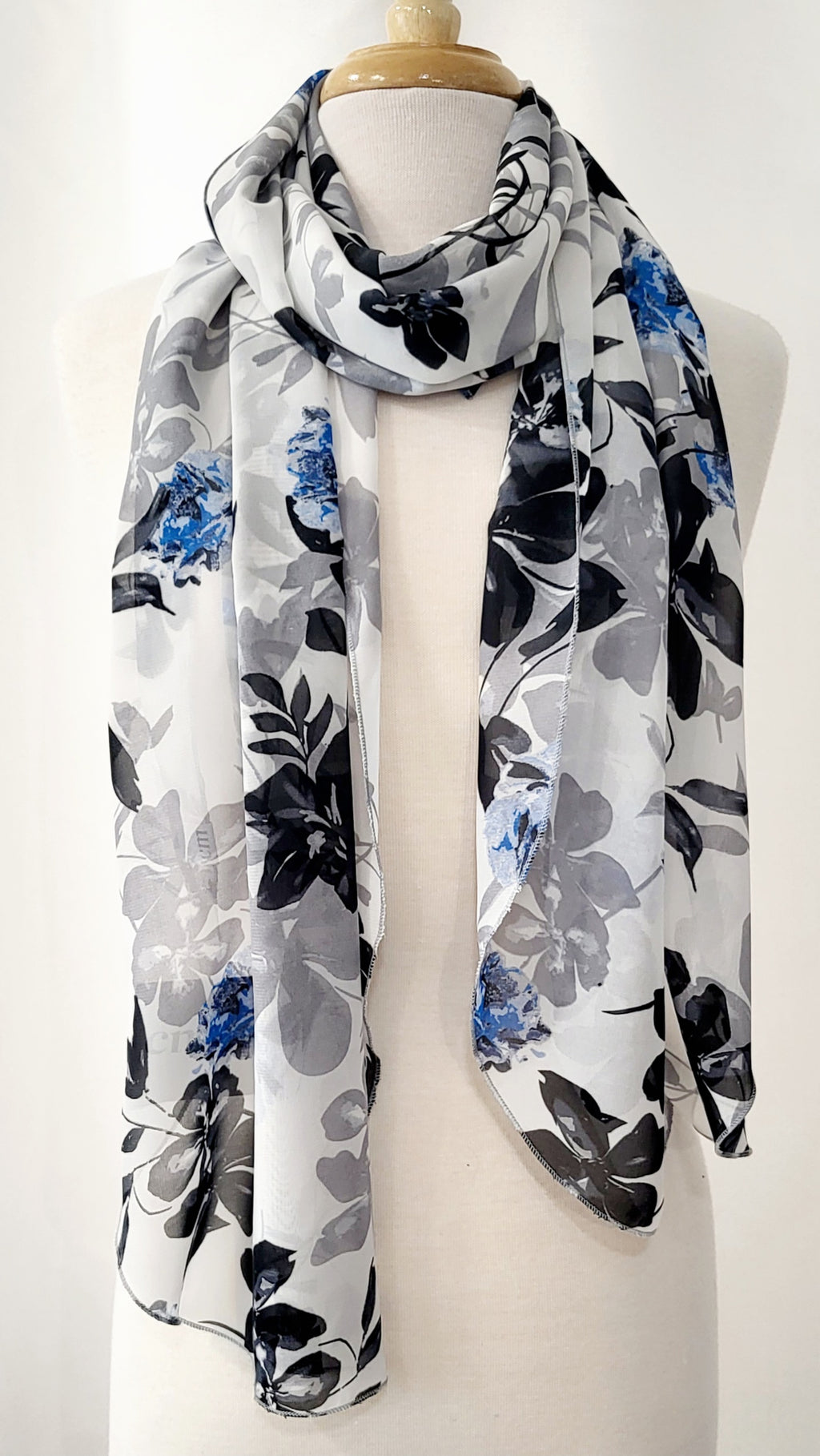 Grand foulard en voilage imprimée de fleurs grises, noires et bleues.