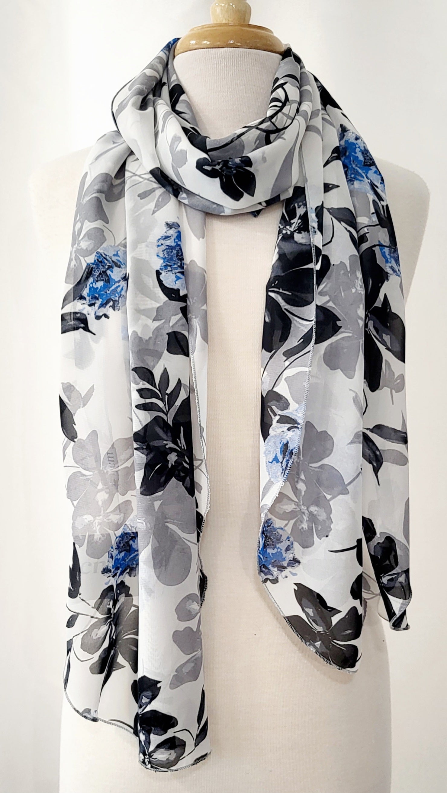 Grand foulard en voilage imprimée de fleurs grises, noires et bleues.