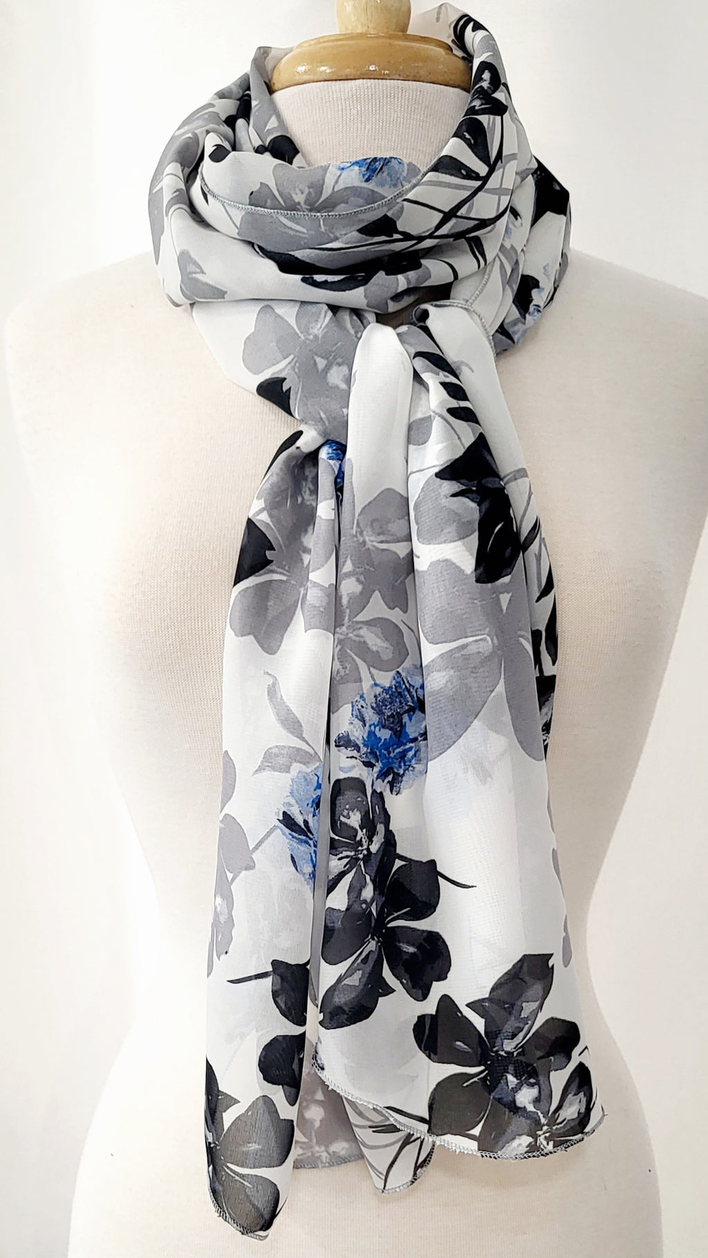 Grand foulard en voilage imprimée de fleurs grises, noires et bleues.