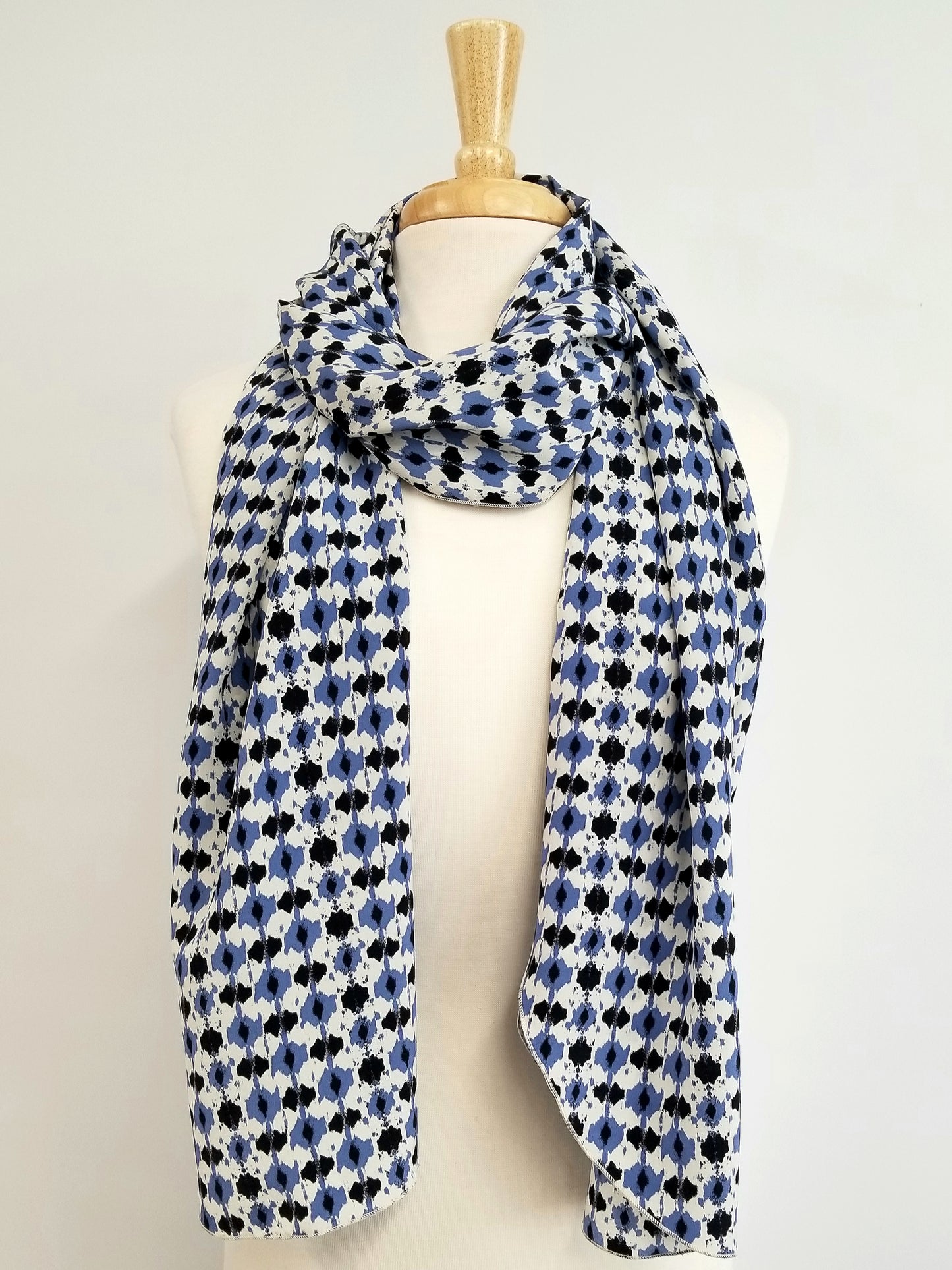 Foulard long en soie, imprimé bleu, noir et blanc cassé.